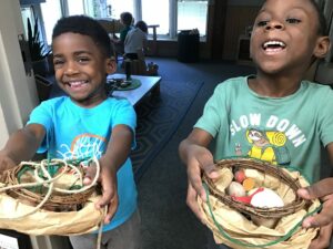 Two boys holding a crafted birds nest with eggs that they made.