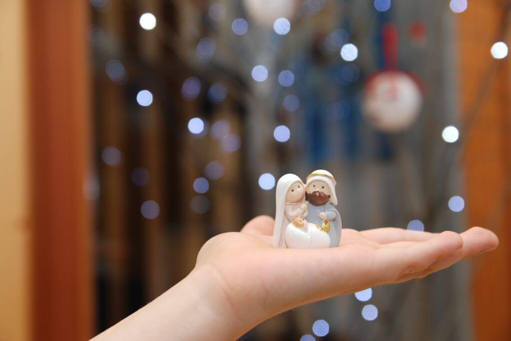 Young child’s hand holding a nativity scene statue