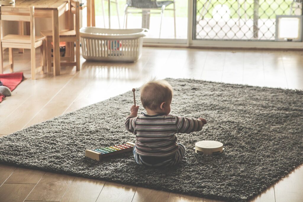 Toddler on carpet playing with instruments