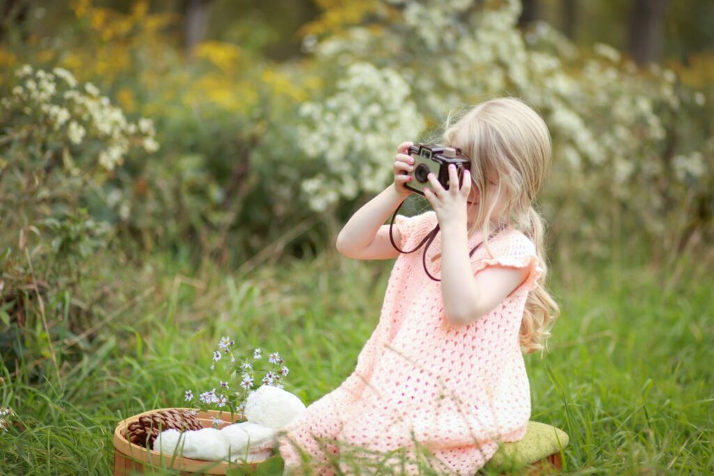 Little girl in the woods taking a picture with a camera