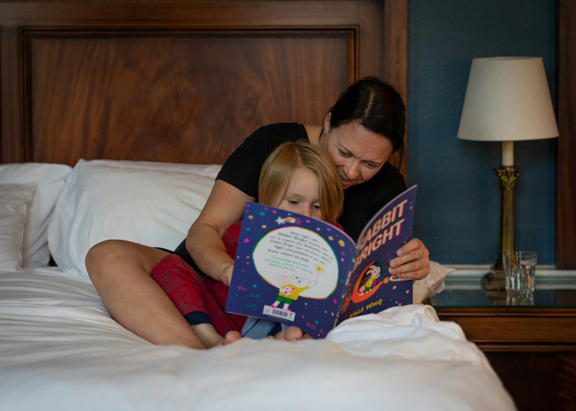 Mother reading a picture book to her son in bed
