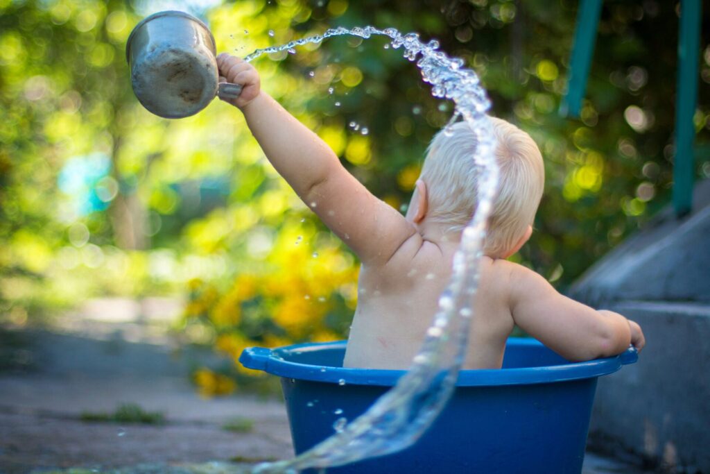 Baby splashing in bucket of water