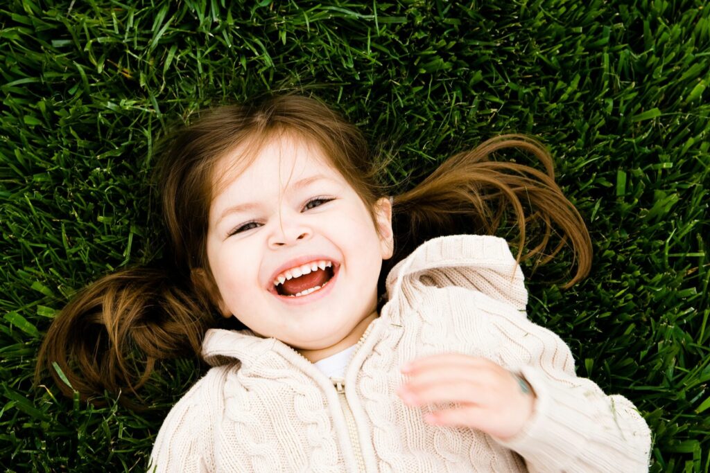 Little girl smiling while laying in the grass