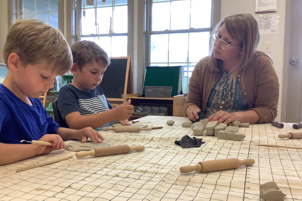 Teacher sitting at a table with 2 young boys.