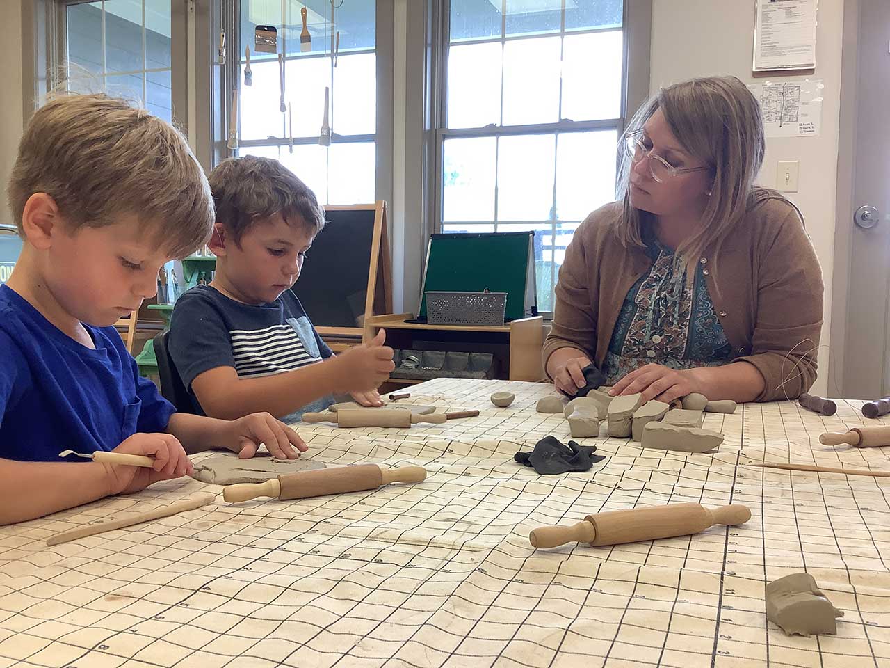 Teacher sitting at a table with 2 young boys.