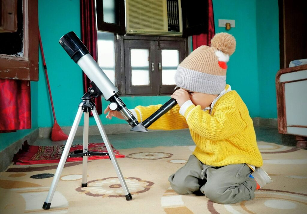toddler-looking-into-telescope Child learning exploring through inquiry-based learning.