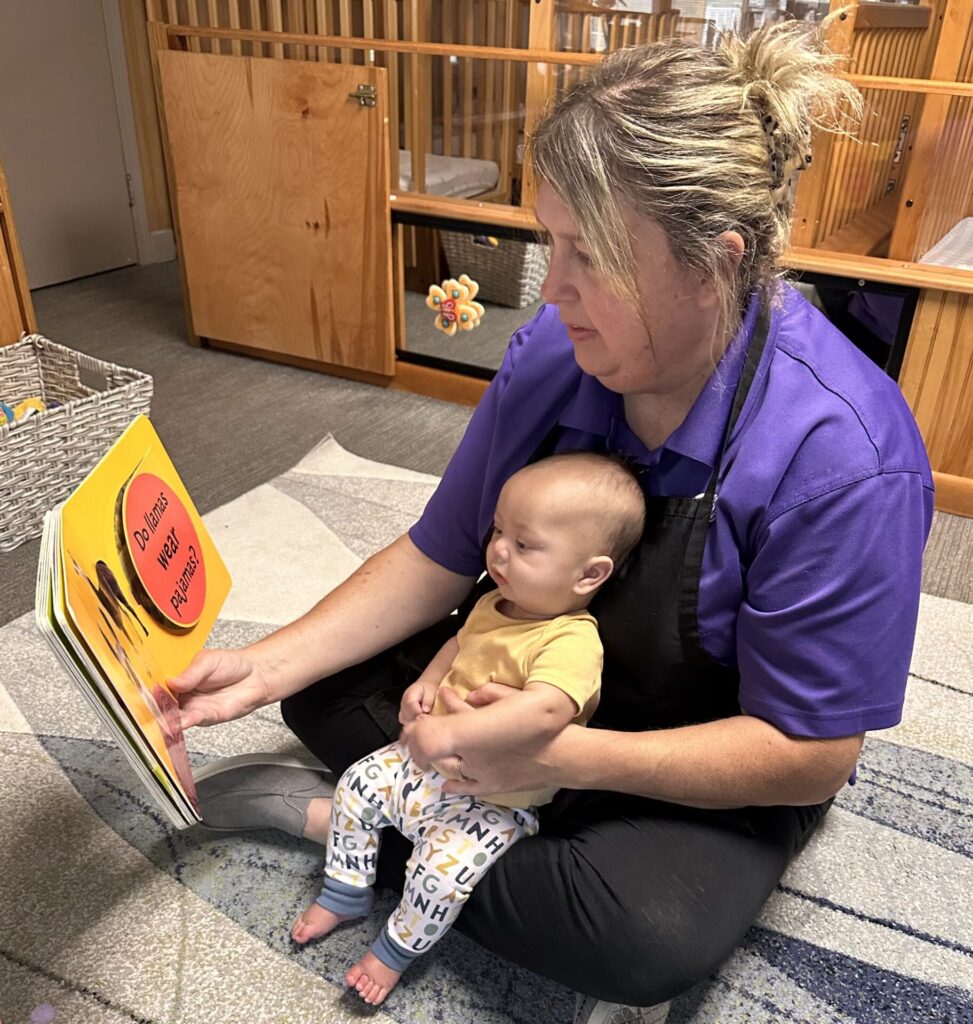 Ms. Angie reading a book to an infant CDC student.