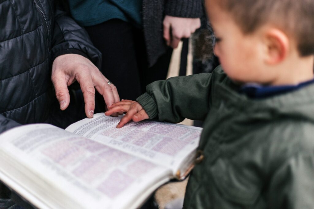 Young child reading bible with his parents
