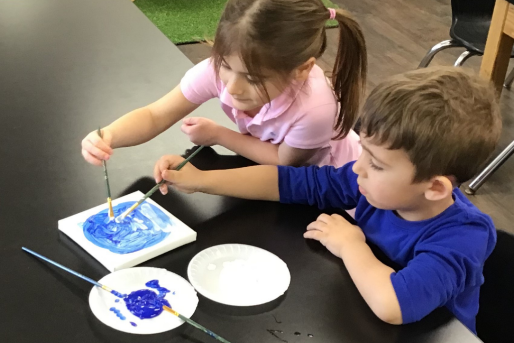 Children painting together and collaborating on an art project.