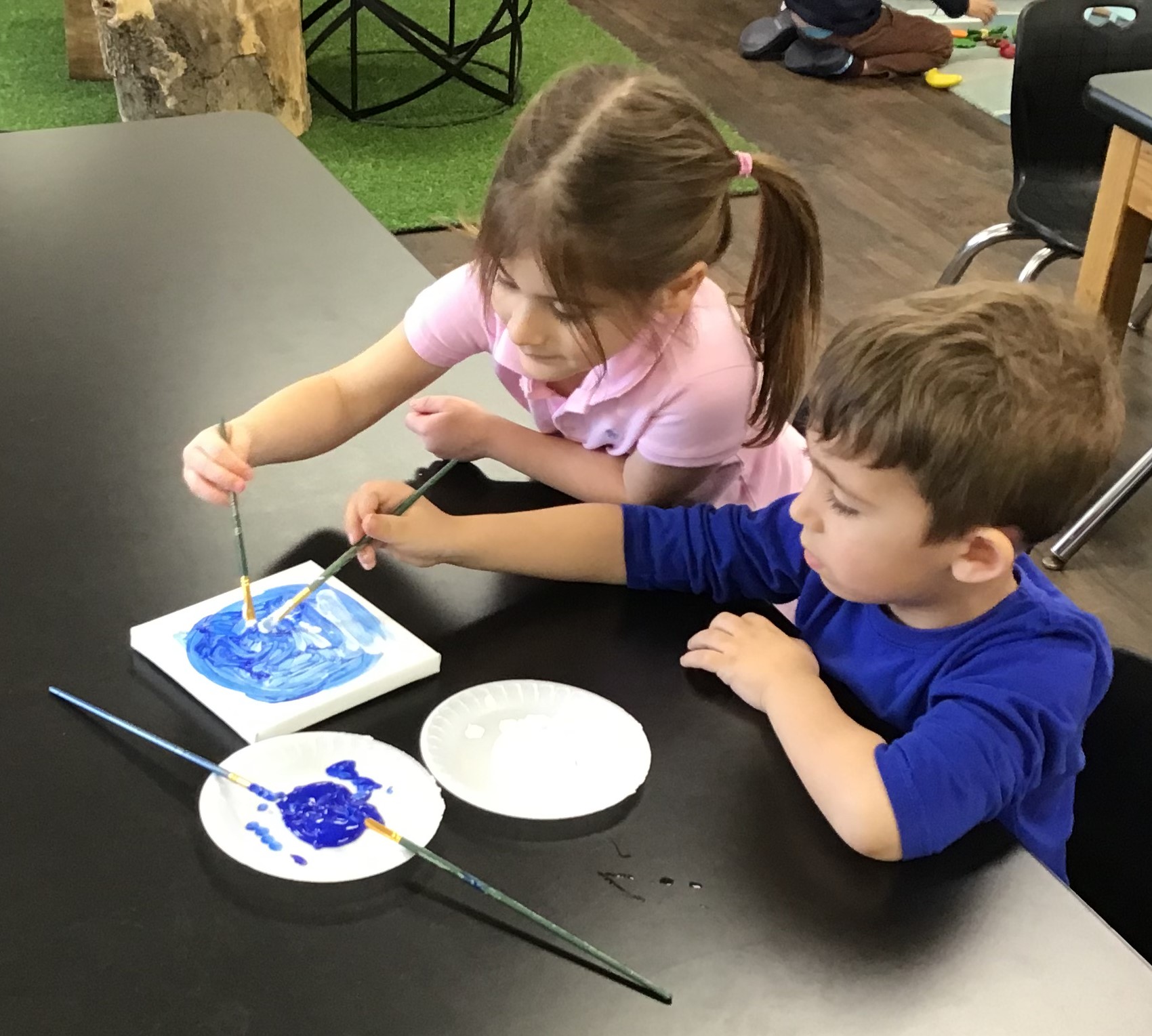 Children painting together and collaborating on an art project.
