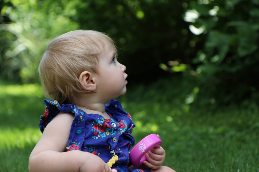 Baby sitting in the grass representing Children’s Discovery Center’s Reggio Emilia-inspired infant care program in Toledo